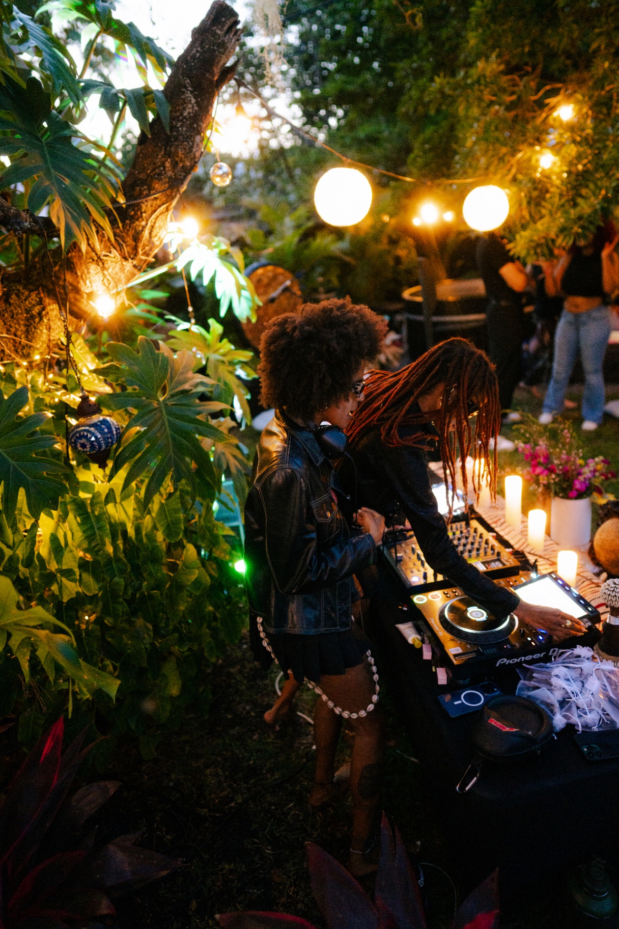 A candlelit garden gathering with DJs spinning under string lights and lanterns